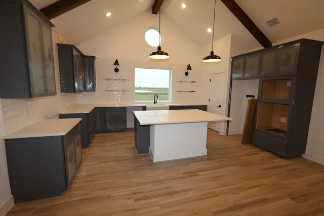 a large kitchen with a large counter top a sink a refrigerator and a stove