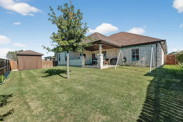 a view of an house with backyard and a tree
