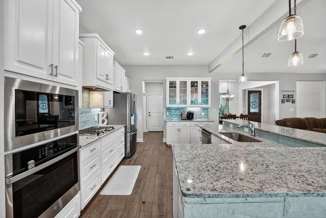 a large kitchen with stainless steel appliances granite countertop a stove oven and a white cabinets