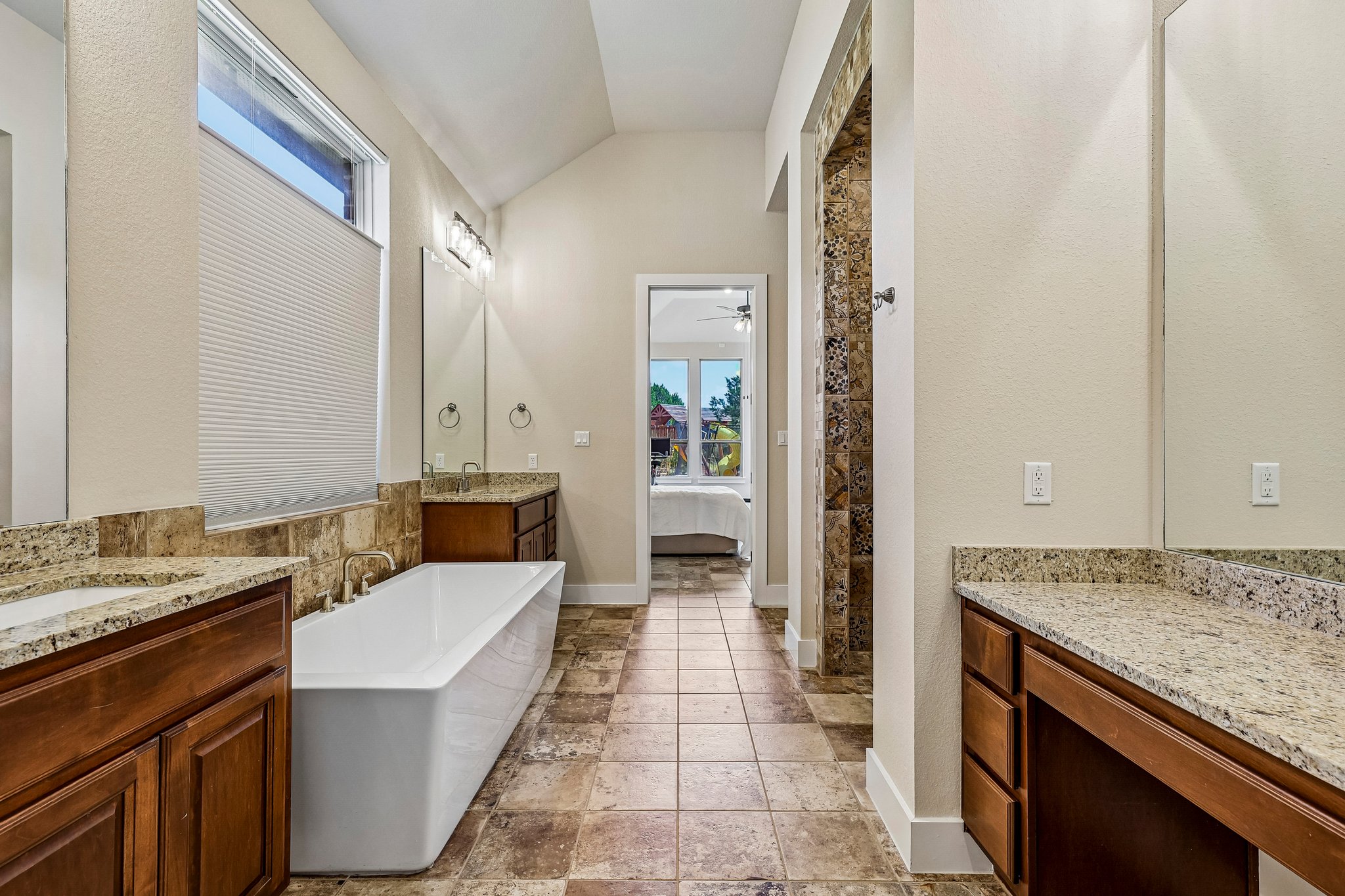 1705 Parten Rnch Parkway Austin, TX 78737 - Photo 27 of 39 A spacious primary bathroom boasts a freestanding tub, dual vanities with granite counters, and a separate tiled shower.