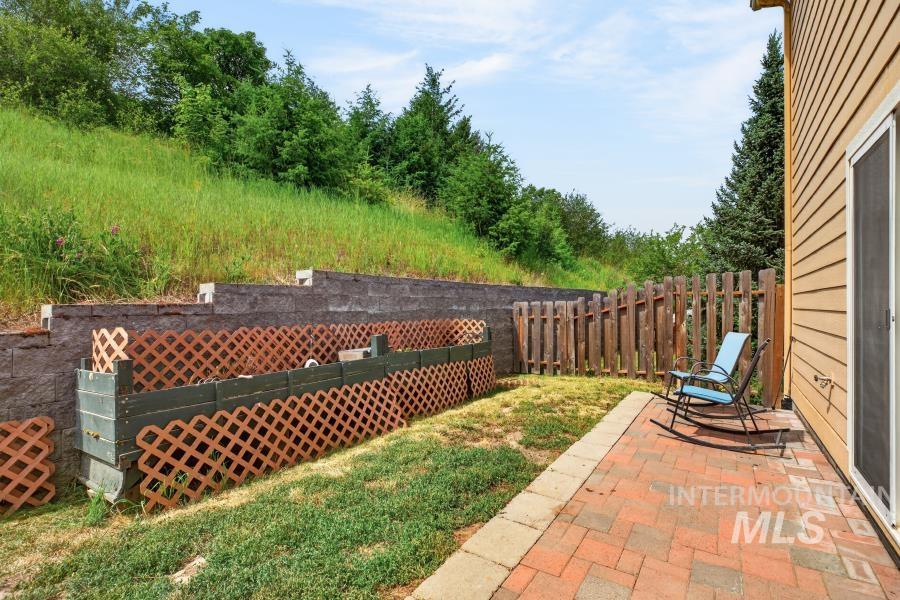 1337 Bristol Road Moscow, ID 83843 - Photo 14 of 28 Brick paver patio with a sliding glass door entry to the property, bordered by a wood privacy fence and retaining walls
