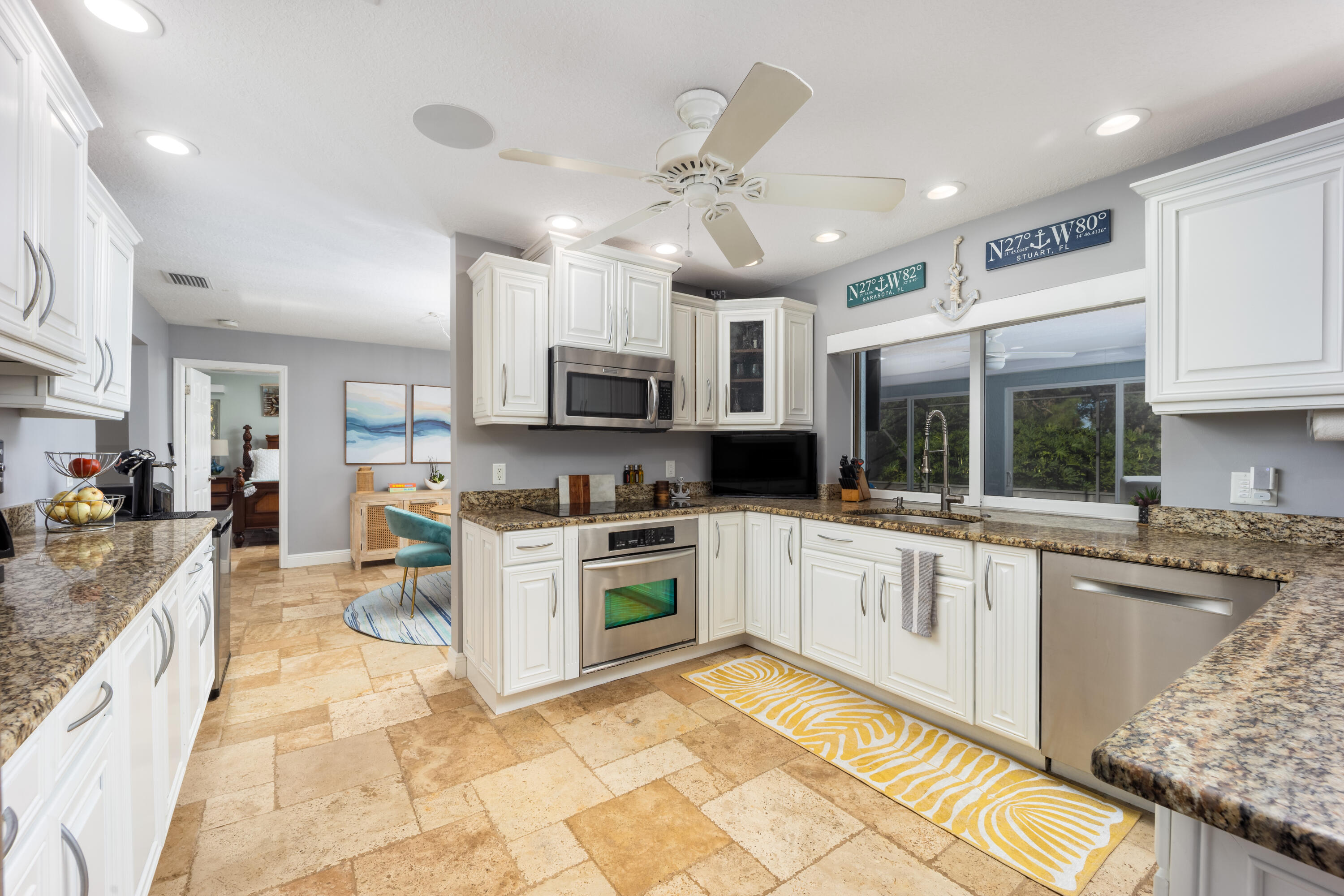3771 Southeast Fairway West Stuart, FL 34997 - Photo 20 of 41 a large kitchen with stainless steel appliances granite countertop a stove top oven a sink dishwasher a dining table and chairs with wooden floor