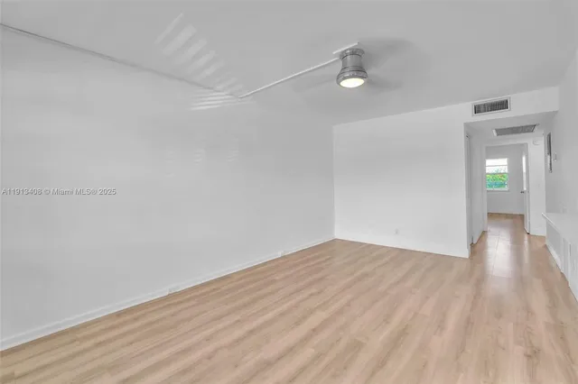 a view of an empty room with window and wooden floor