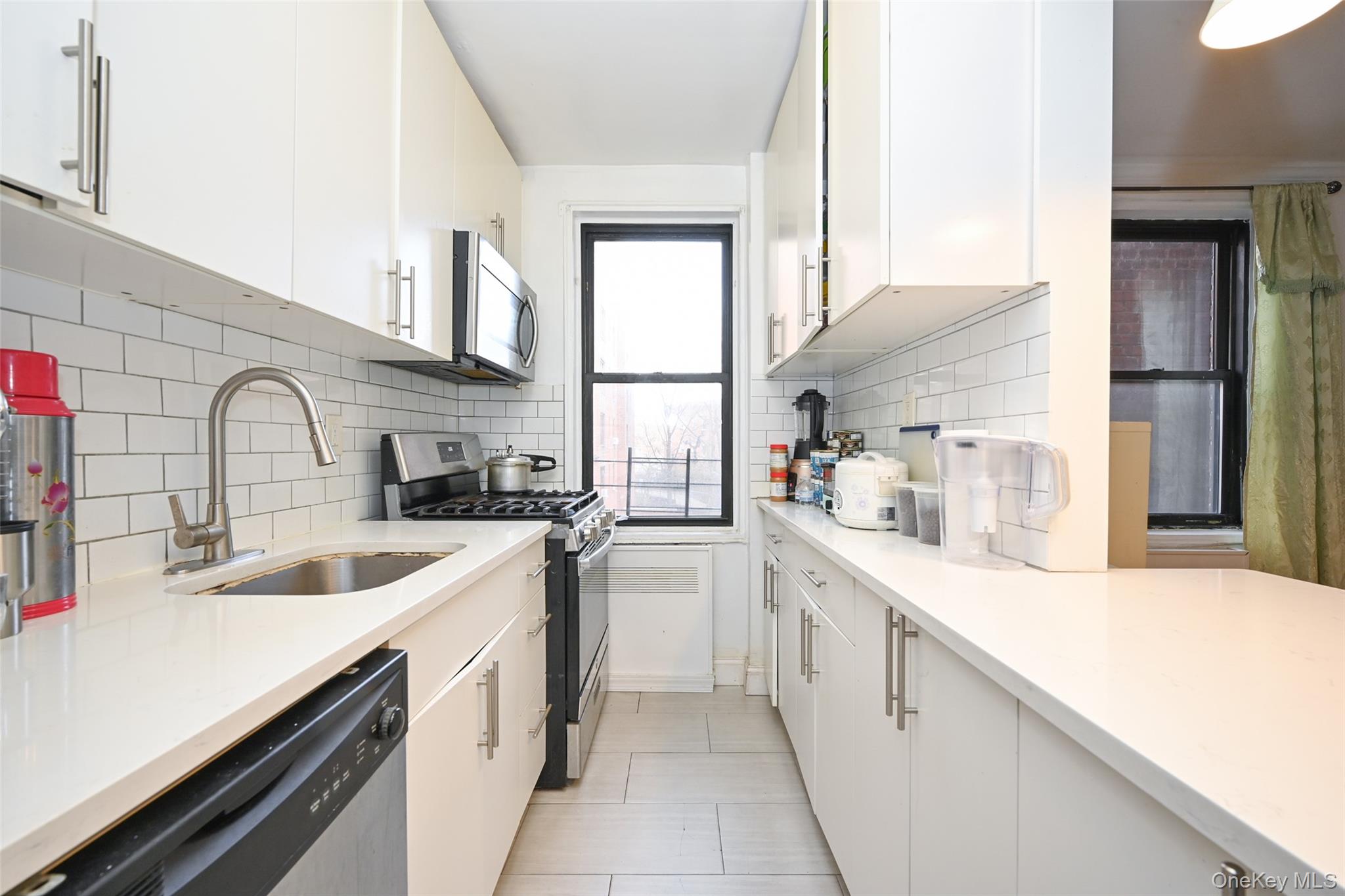 150-30 71st Avenue, Unit 2F Queens, NY 11367 - Photo 3 of 19 Kitchen featuring appliances with stainless steel finishes, white cabinetry, light stone countertops, and decorative backsplash