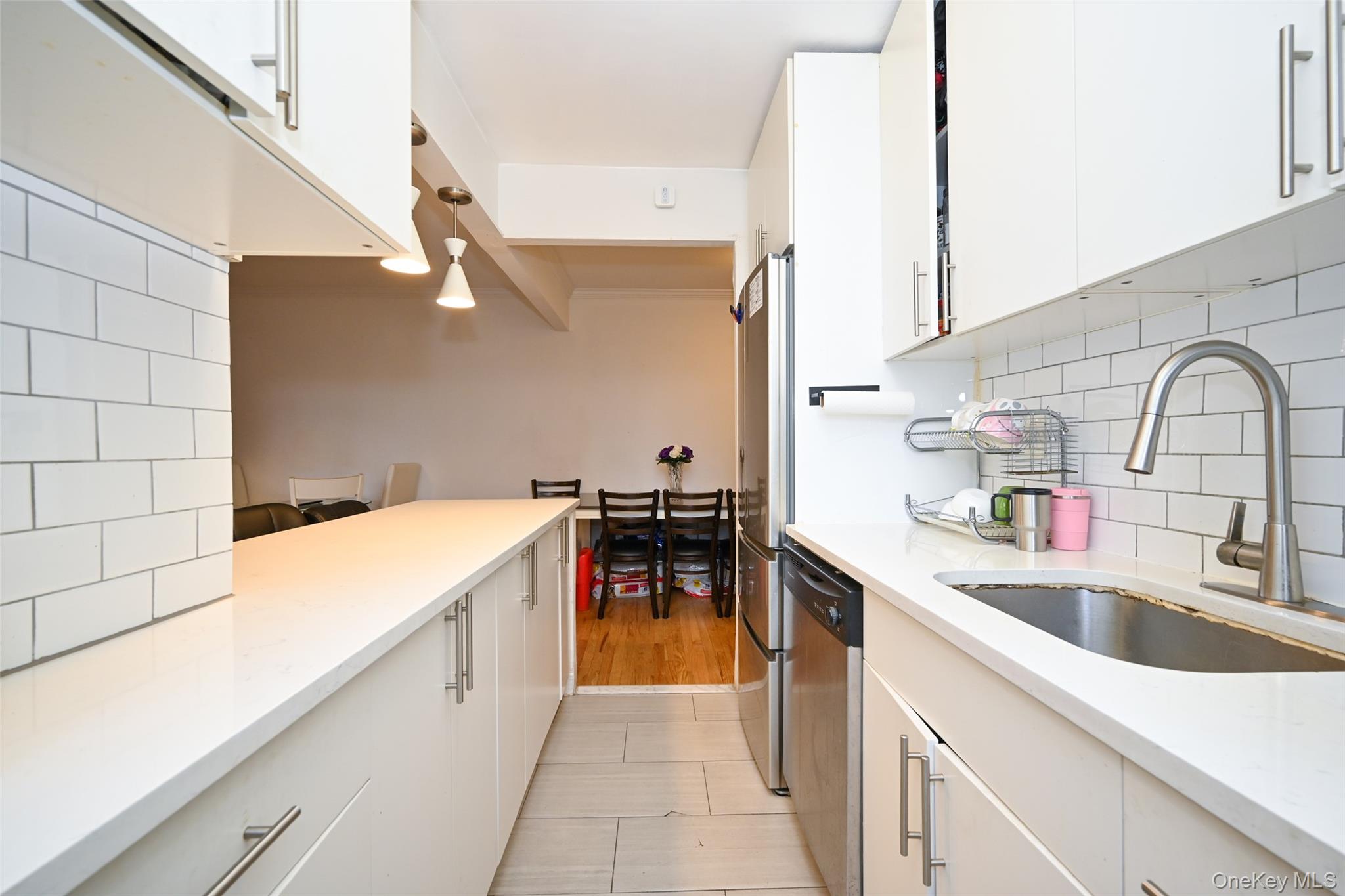 150-30 71st Avenue, Unit 2F Queens, NY 11367 - Photo 4 of 19 Kitchen with backsplash, white cabinetry, decorative light fixtures, and appliances with stainless steel finishes