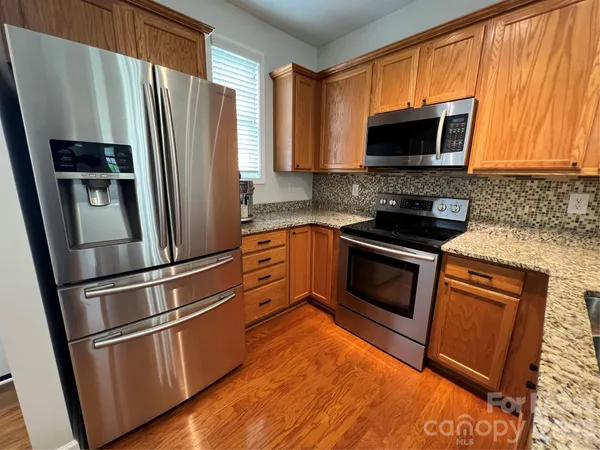 a kitchen with granite countertop a refrigerator stove and microwave