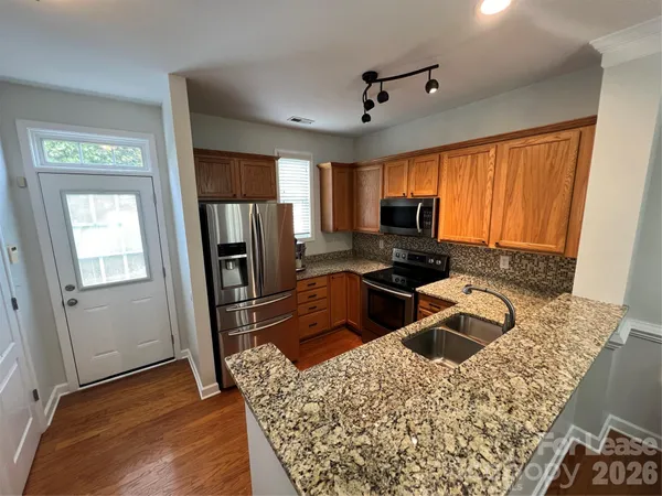 a kitchen with granite countertop a refrigerator stove and sink