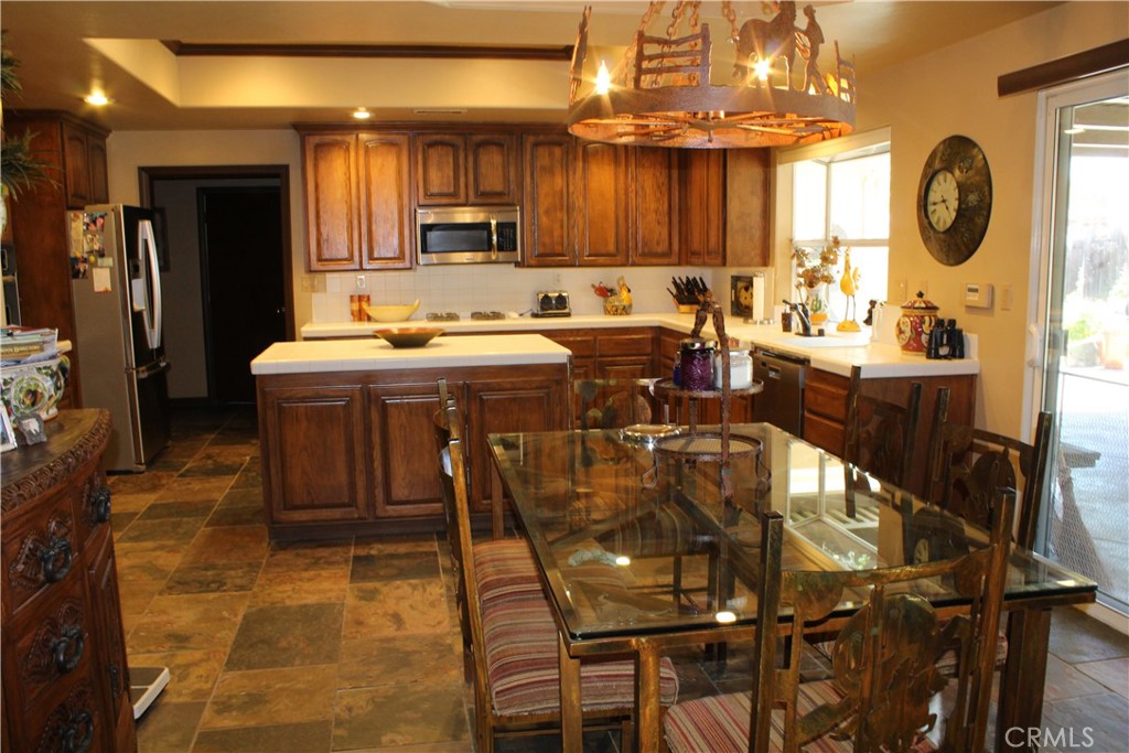 4937 Sweetgrass Lane Bonsall, CA 92003 - Photo 33 of 33 a kitchen with stainless steel appliances kitchen island granite countertop a table chairs sink and cabinets