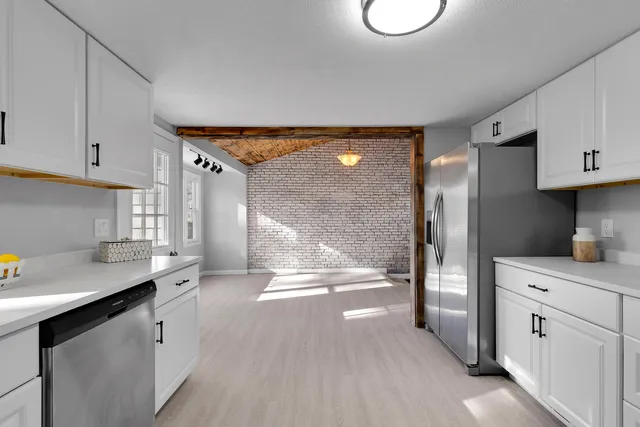 a kitchen with white cabinets and window