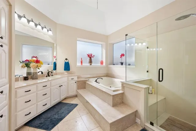 a spacious bathroom with a granite countertop sink a mirror a bathtub and shower