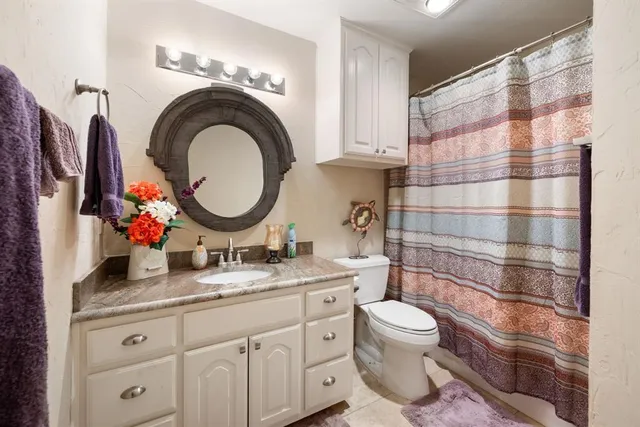 a bathroom with a granite countertop toilet sink and mirror