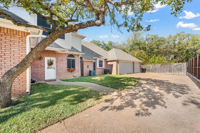a view of a yard in front of a house with a large tree
