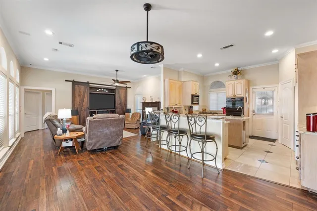 a living room with furniture kitchen view and a wooden floor