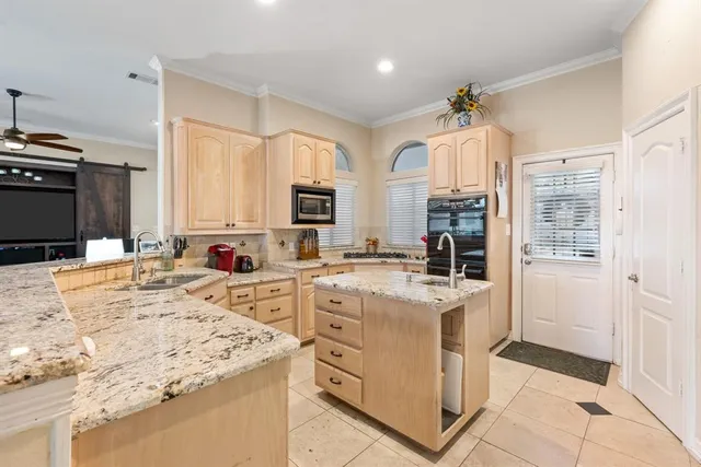 a kitchen with stainless steel appliances kitchen island granite countertop a stove top oven a sink dishwasher and white cabinets with wooden floor