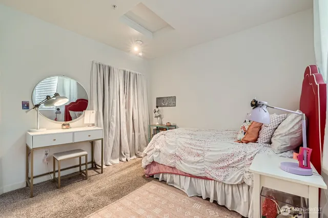 a bedroom with a bed a chandelier and dresser