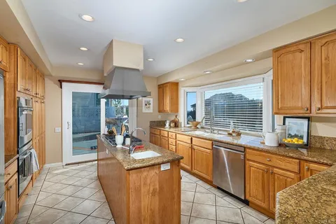 a kitchen with stainless steel appliances granite countertop a sink dishwasher stove and refrigerator with wooden floor