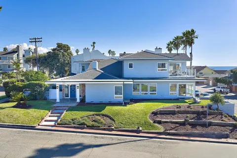 front view of a house with a small yard and a large tree