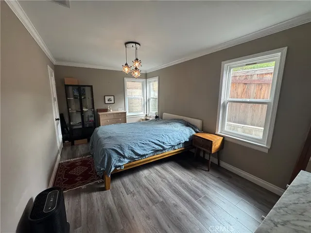a bedroom with a bed windows and wooden floor