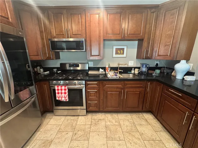 a kitchen with stainless steel appliances granite countertop a stove a sink and a microwave