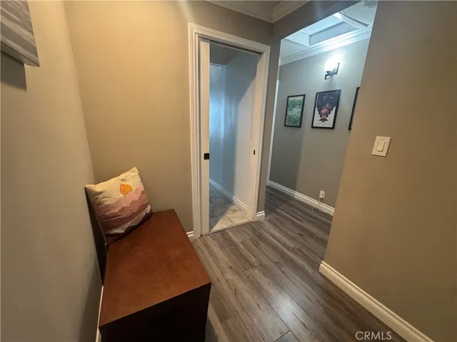 a view of a hallway with wooden floor and a bathroom