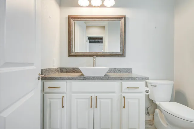 a bathroom with a granite countertop toilet sink and mirror