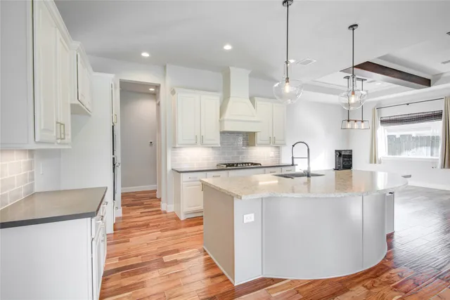 a large kitchen with stainless steel appliances granite countertop a sink a stove and a wooden floors