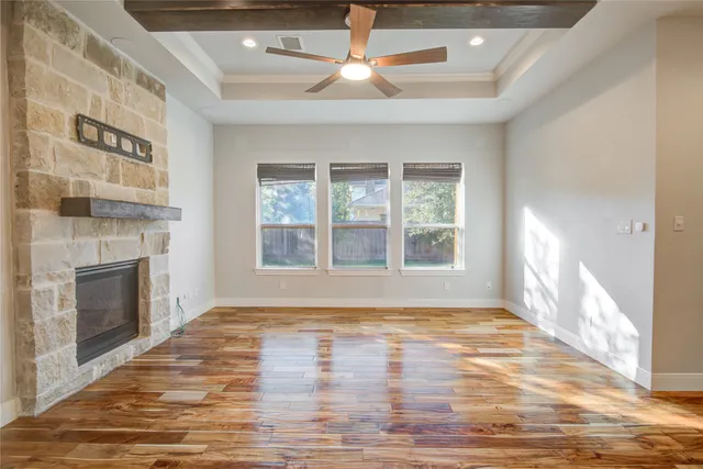 a view of an empty room with window and wooden floor