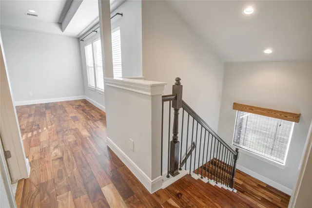 a view of an empty room with a ceiling fan and wooden floor