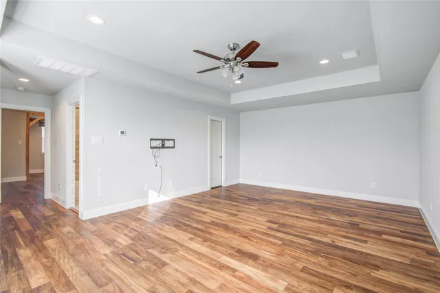 a view of empty room with wooden floor and fan