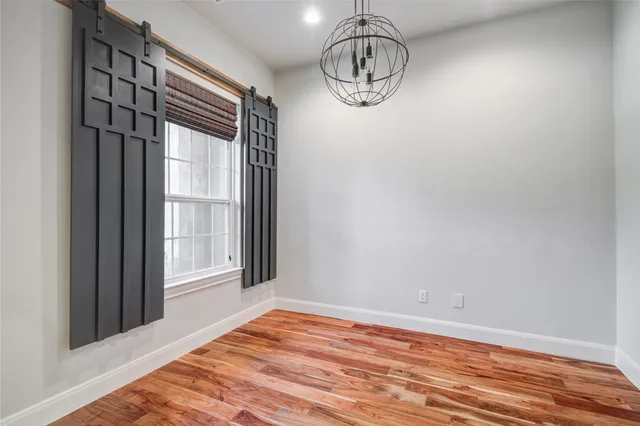 a view of empty room with wooden floor and window