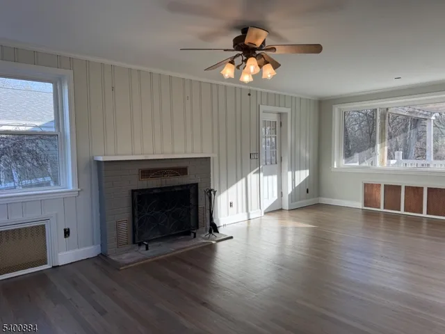 an empty room with wooden floor a fireplace and windows