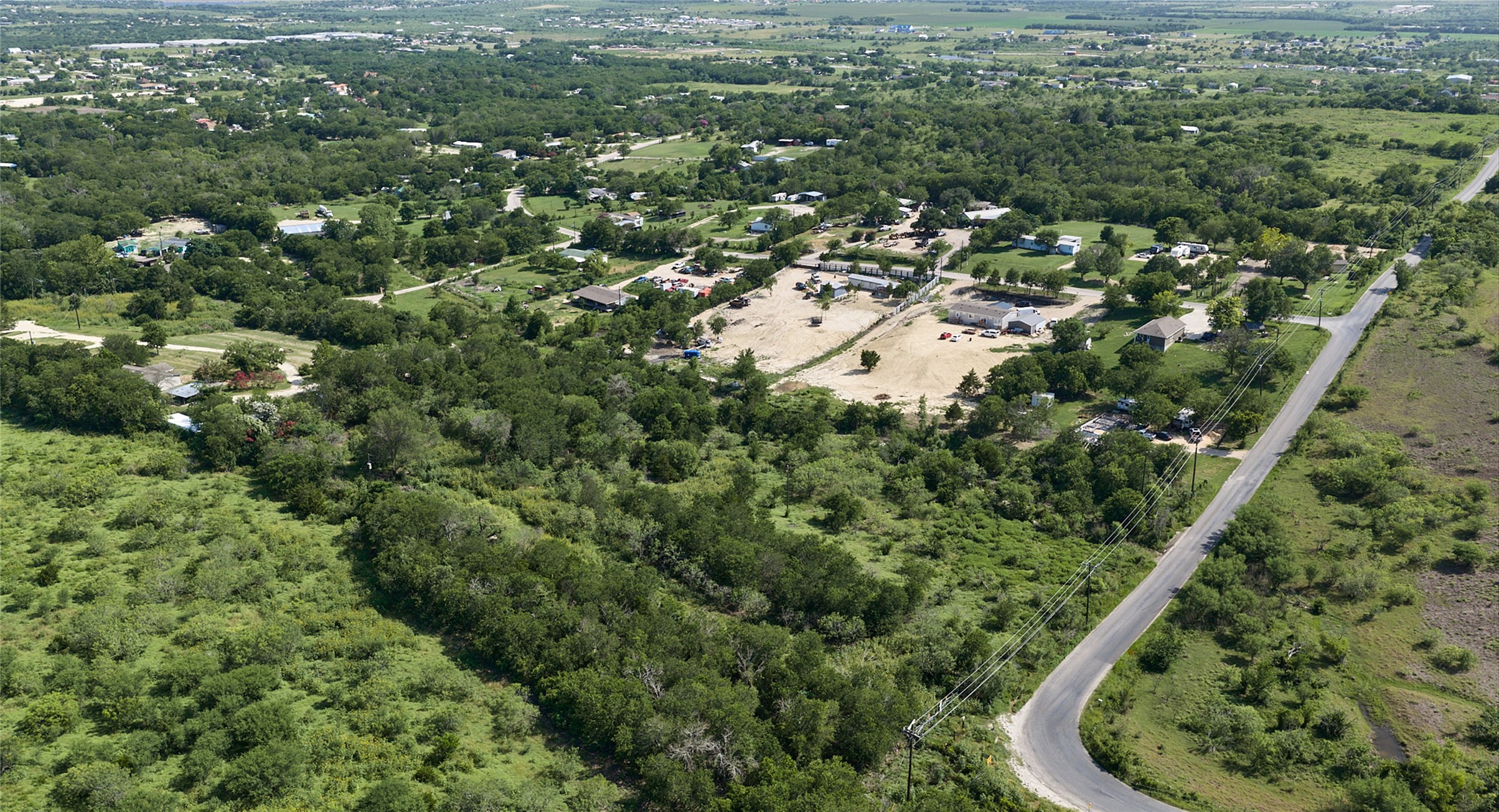 1400 Williamson Road Kyle, TX 78640 - Photo 5 of 13 An aerial panorama reveals verdant, rolling hills with scattered residential structures and winding pathways.