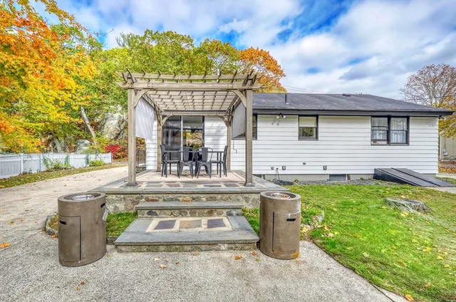a backyard of a house with table and chairs and potted plants