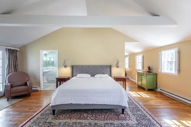 a large bedroom with a bed and wooden floor