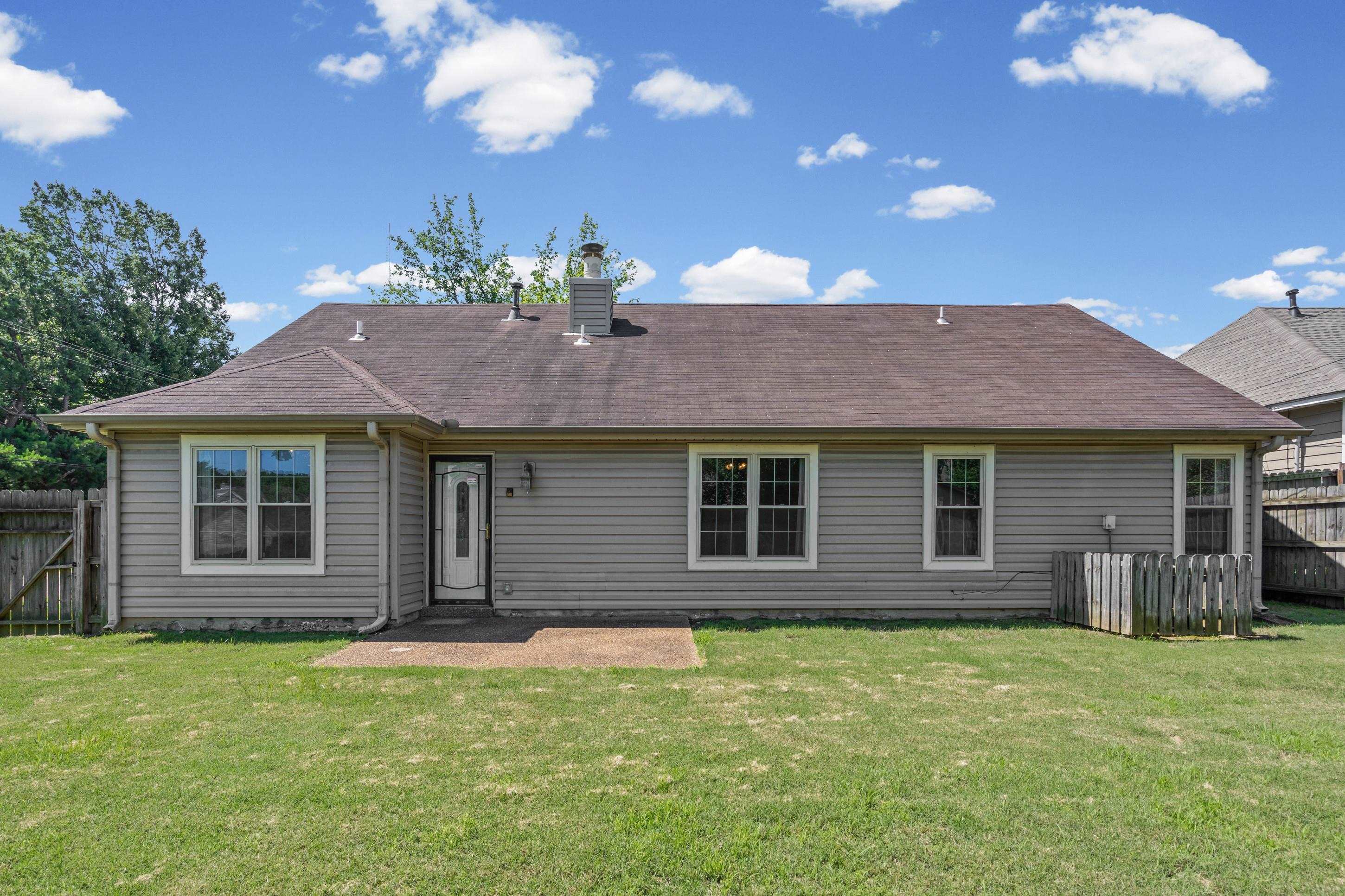 7130 Bryan Station Road Cordova, TN 38018 - Photo 21 of 26 Rear exterior featuring siding, multiple windows, a rear entry door with a divided light insert, a concrete patio, and a grass lawn