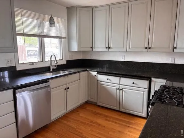 a kitchen with granite countertop white cabinets and a sink