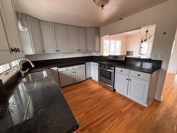 a kitchen with granite countertop a sink a stove and cabinets