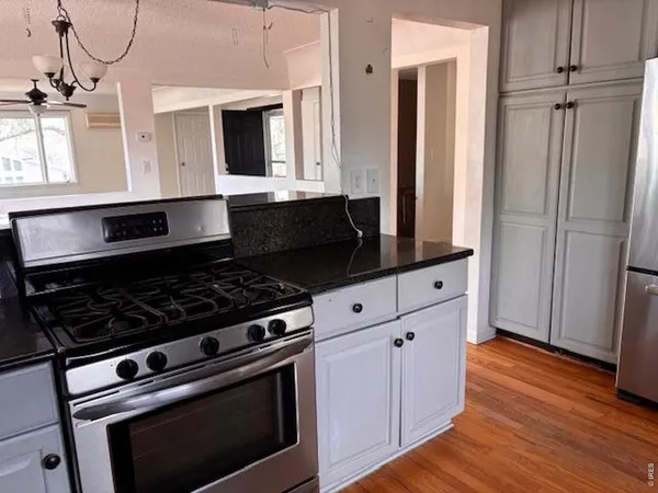 a kitchen with granite countertop a stove and a wooden floor