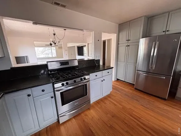 a kitchen with granite countertop a refrigerator and a stove top oven