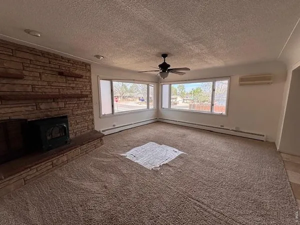 an empty room with windows and fireplace