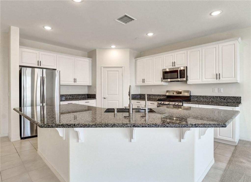 43885 Arancia Way Indio, CA 92203 - Photo 6 of 22 a kitchen with stainless steel appliances granite countertop a refrigerator a stove a sink a microwave and white cabinets