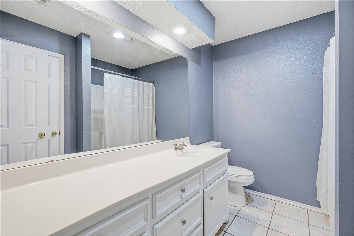 6214 6th Street Lubbock, TX 79416 - Photo 15 of 21 a bathroom with a toilet sink and mirror