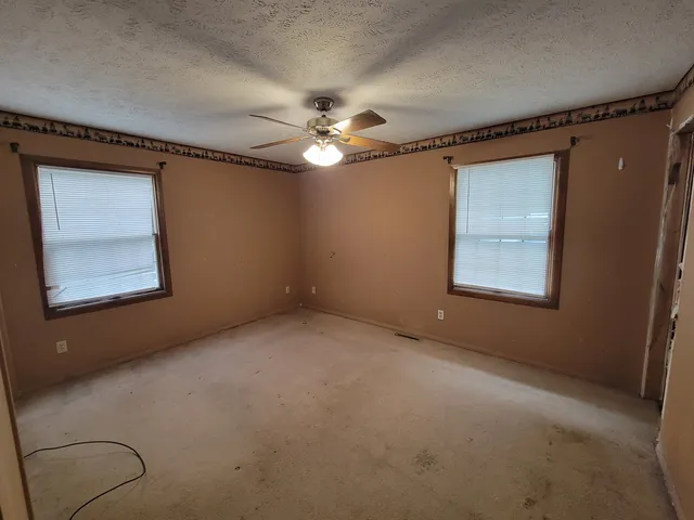 an empty room with windows and fan