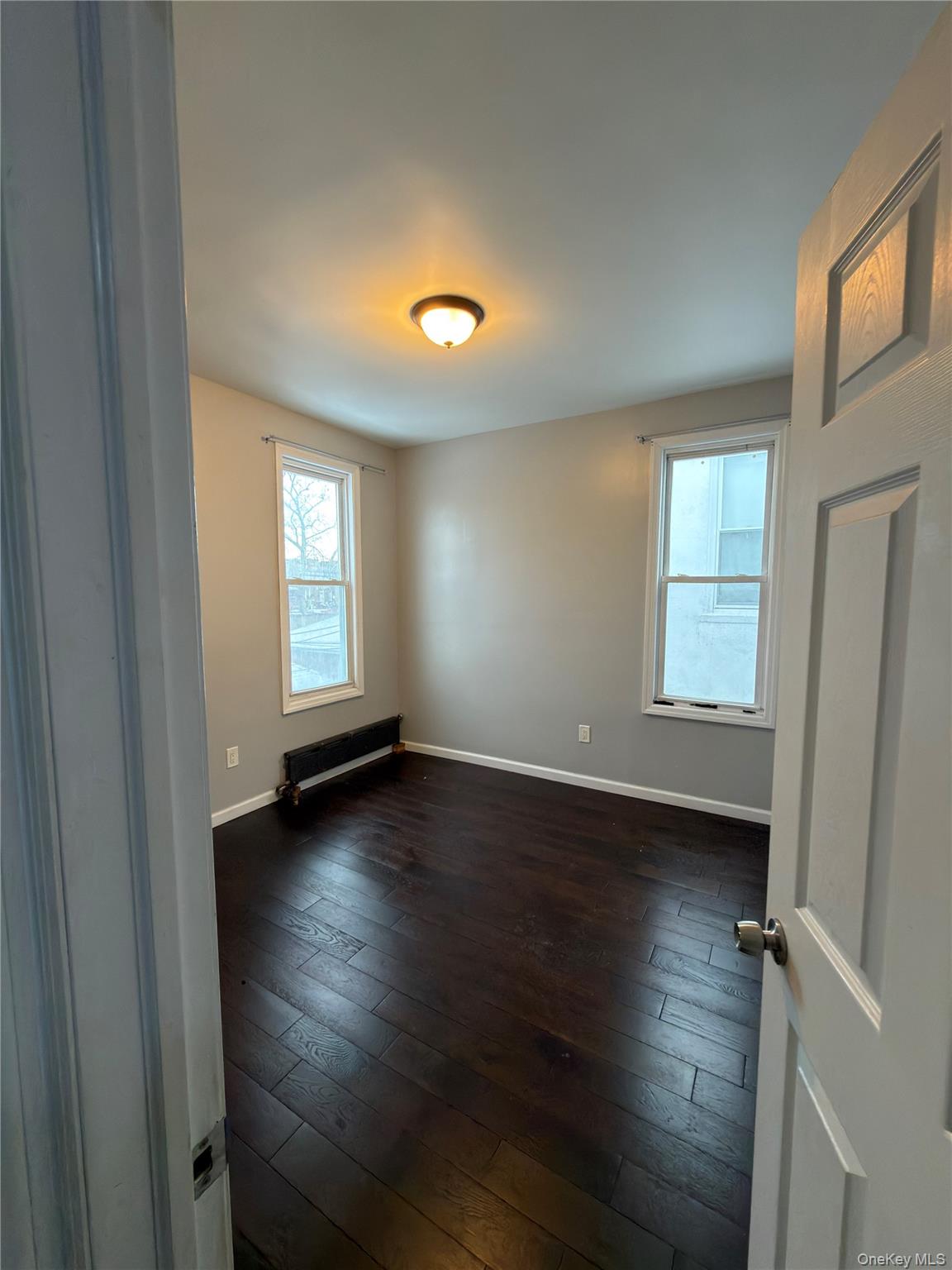31-45 84th Street, Unit 2 Queens, NY 11370 - Photo 3 of 5 an empty room with wooden floor and windows