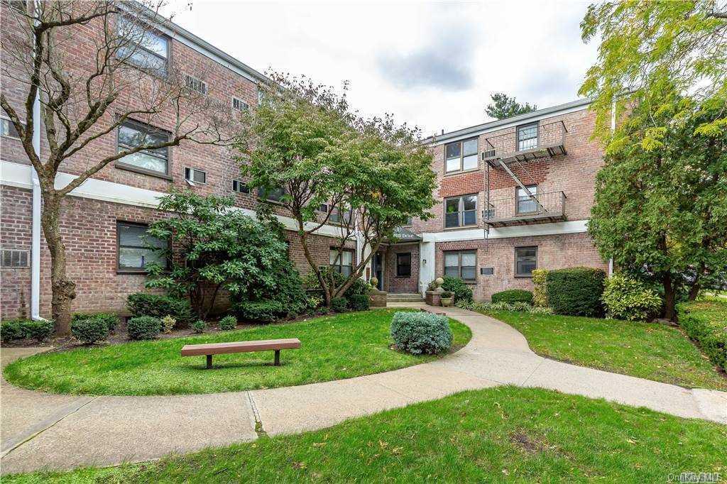 a view of a white house next to a yard with big trees