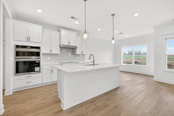 a kitchen with stainless steel appliances granite countertop a sink a stove a refrigerator and white cabinets