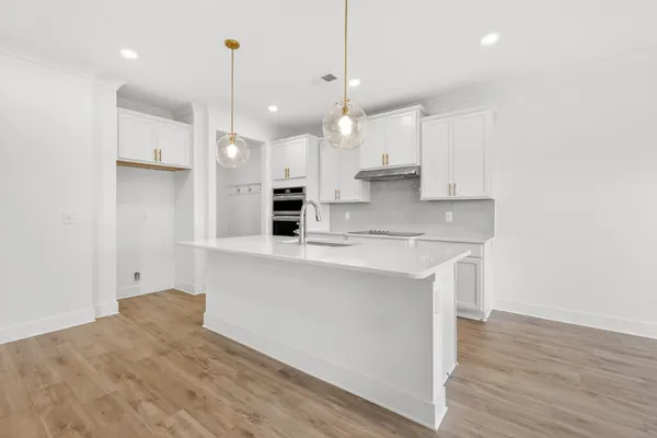 a kitchen with a sink a stove a refrigerator and white cabinets