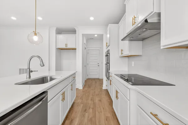 a kitchen with stainless steel appliances granite countertop a sink a stove and a wooden floor