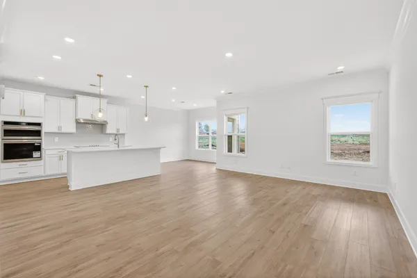 a view of kitchen with kitchen island a sink wooden floor and a refrigerator