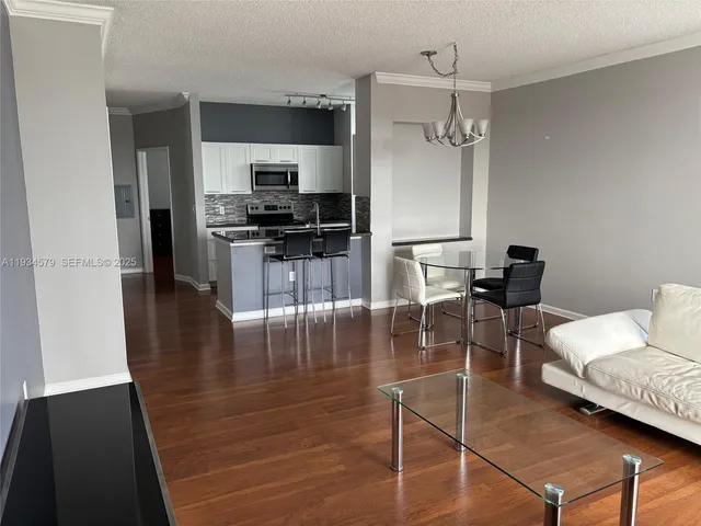 a kitchen with stainless steel appliances kitchen island granite countertop a refrigerator a stove and a dining table with wooden floor